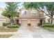 Two-story tan home featuring a well-manicured lawn, two-car garage, and charming stone accents at 11839 Castine St, New Port Richey, FL 34654