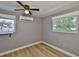 Bright bedroom with wood flooring, two windows, and AC unit at 12468 Empire Dr, Seminole, FL 33772