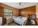Bedroom featuring wood-paneled walls, a ceiling fan, and natural light from the window at 12803 126Th Ter, Largo, FL 33774