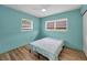 Bedroom features blue walls, wood-look flooring, ceiling fan, and natural light at 1412 Coburn Dr, Tarpon Springs, FL 34689
