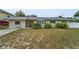 Charming home featuring a well-kept lawn, mature bushes, and a red front door at 1412 Coburn Dr, Tarpon Springs, FL 34689