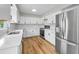 Bright kitchen featuring white cabinets, stainless steel appliances, and wood-look flooring at 1412 Coburn Dr, Tarpon Springs, FL 34689