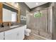 Bathroom featuring a glass-enclosed shower with pebble flooring and a gray tiled surround, plus a wood-framed mirror at 14223 Lambert Bridge Ln, Lithia, FL 33547