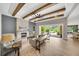 Open-concept living room with fireplace and beamed ceilings and access to outdoor living at 14223 Lambert Bridge Ln, Lithia, FL 33547