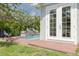 A charming backyard featuring a pool with a stone waterfall, surrounded by lush greenery and brick patio at 152 Glenn Moor Cir, Dunedin, FL 34698