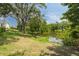 Expansive backyard featuring a serene pond, lush green lawn, and mature trees offering ample shade at 152 Glenn Moor Cir, Dunedin, FL 34698