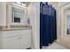 Well-lit bathroom featuring a granite countertop vanity and a shower with a blue curtain at 152 Glenn Moor Cir, Dunedin, FL 34698