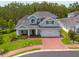 Eye-level shot of a beautiful two-story home with a manicured lawn and brick driveway in a serene neighborhood at 152 Glenn Moor Cir, Dunedin, FL 34698