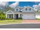 Charming two-story home with a well-manicured lawn, brick driveway, and a welcoming front porch with rocking chairs at 152 Glenn Moor Cir, Dunedin, FL 34698