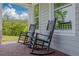 Relaxing front porch featuring rocking chairs, brick flooring and serene views of the surrounding greenery at 152 Glenn Moor Cir, Dunedin, FL 34698