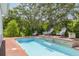 Inviting pool featuring brick patio, stone waterfall, and chairs, with lush greenery and black fence at 152 Glenn Moor Cir, Dunedin, FL 34698