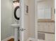 Charming powder room featuring a pedestal sink, decorative mirror, and views into the laundry room at 152 Glenn Moor Cir, Dunedin, FL 34698