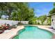 Private backyard oasis featuring a kidney-shaped pool, lounge chairs, and lush landscaping behind a white fence at 15801 Cottontail Pl, Tampa, FL 33624