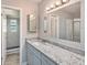 Updated bathroom with granite countertops, a large mirror, and a tiled walk-in shower at 15801 Cottontail Pl, Tampa, FL 33624