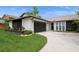 Charming single-story home featuring stucco siding, a dark two-car garage, and well-manicured landscaping at 15801 Cottontail Pl, Tampa, FL 33624