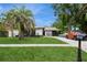 Charming single-story home featuring a lush green lawn, a mature palm tree, and a neatly paved driveway at 15801 Cottontail Pl, Tampa, FL 33624