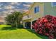 Multi-story home with yellow and green exterior and white balconies, showcasing a well-maintained lawn and colorful plants at 17 Franklin S Ct # C, St Petersburg, FL 33711