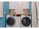 Well-equipped laundry room with a wooden countertop, white cabinets, and modern washer/dryer units at 18827 Henequen Lane, Spring Hill, FL 34610