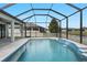 Outdoor pool with a waterfall feature in a screened enclosure, offering views of surrounding homes at 18827 Henequen Lane, Spring Hill, FL 34610
