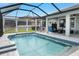Inviting pool area with seating, covered patio, and a clear view of the pool's waterfall feature at 18827 Henequen Lane, Spring Hill, FL 34610