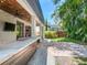 Covered patio with outdoor kitchen, TV, ceiling fan, and lush green landscaping at 3003 W Leila Ave, Tampa, FL 33611