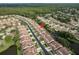 Bird's-eye view showcases the community layout with uniform red-tiled roofs, lush green spaces, and a serene waterway running through it at 3875 Darston St, Palm Harbor, FL 34685