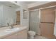 Well-lit bathroom featuring a large mirror, single sink, and a glass-enclosed shower with handrails for accessibility at 3875 Darston St, Palm Harbor, FL 34685