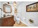 Classic powder room with a decorative mirror, vanity, toilet, and artwork, providing a stylish space at 3903 W De Leon St, Tampa, FL 33609
