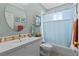 Well-lit bathroom featuring a single sink vanity, toilet, and a shower with a blue curtain at 502 Lincoln Ave, Tarpon Springs, FL 34689