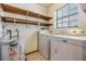 Bright laundry room featuring a washer, dryer, water heater and open shelving above the appliances at 507 4Th Sw Ave, Largo, FL 33770