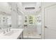 The renovated bathroom boasts white tiles, a glass enclosed shower, and natural light at 5102 White Pine Ne Cir, St Petersburg, FL 33703