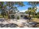 Charming single-story home with mature trees, gravel drive, and covered parking at 5270 Miller Bayou Dr, Port Richey, FL 34668