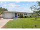 Single story home with gray exterior, showing garage door, blue door, landscaping, manicured lawn and multi-pane windows at 5961 41St N Ave, St Petersburg, FL 33709