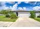 Charming single Gathering home featuring a two-car garage and landscaped front yard with lush green grass and plants at 6119 Bradford Woods Dr, Zephyrhills, FL 33542