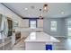 Bright kitchen with white cabinets, quartz countertops, a blue island, and modern stainless steel appliances at 6119 Bradford Woods Dr, Zephyrhills, FL 33542