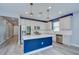 Modern kitchen with stainless steel appliances, white cabinets, quartz countertops, and a blue kitchen island at 6119 Bradford Woods Dr, Zephyrhills, FL 33542