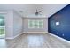 Living room featuring modern wood-look floors, a ceiling fan, and a bold blue accent wall adding a touch of color at 6119 Bradford Woods Dr, Zephyrhills, FL 33542