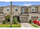 Close up of tan townhomes with garages and a red car parked in front at 6924 Towne Lake Rd, Riverview, FL 33578