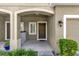 Inviting covered front porch with a brown front door, green plants, and neutral paint at 6924 Towne Lake Rd, Riverview, FL 33578