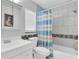 Bright bathroom with shower-tub combo, white vanity and toilet complemented by a decorative shower curtain at 6960 Sunset S Dr # 2B, South Pasadena, FL 33707