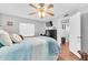Cozy bedroom featuring a ceiling fan, TV, wood floor and comfortable bed with a blue and white comforter at 6960 Sunset S Dr # 2B, South Pasadena, FL 33707
