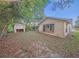 View of backyard with overgrown brush and a detached garage at 7033 Wentworth Way, New Port Richey, FL 34655