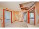 Room with peeling wallpaper, damaged wall, open ceiling, and damaged floors at 7033 Wentworth Way, New Port Richey, FL 34655