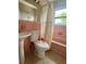 Bathroom featuring a pedestal sink, toilet, and a bathtub with pink tiles and neutral flooring at 72 Lake Shore Dr, Palm Harbor, FL 34684