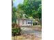 Home exterior showcasing lush trees, flowering bushes, and a concrete driveway at 72 Lake Shore Dr, Palm Harbor, FL 34684