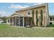 Home exterior featuring a screened patio, garden, and blue skies at 9322 Via Segovia, New Port Richey, FL 34655