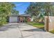 Charming home with a covered front porch, lush landscaping, and a spacious driveway leading to a one-car garage at 1045 28Th S Ave, St Petersburg, FL 33705