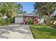 Charming home featuring a covered front porch and driveway leading to a garage, all framed by mature trees at 1045 28Th S Ave, St Petersburg, FL 33705