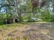 Large backyard with an outbuilding, mature trees providing ample shade and a distant view of the home at 10930 Marjory Ave, Tampa, FL 33612