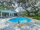 Backyard pool featuring a tranquil poolside statue, complemented by lush landscaping and shaded trees at 10930 Marjory Ave, Tampa, FL 33612